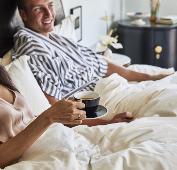 Happy couple lying in bed drinking coffee