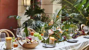 Table set with plates, cutlery, bowls of fruit, candles and flower arrangements