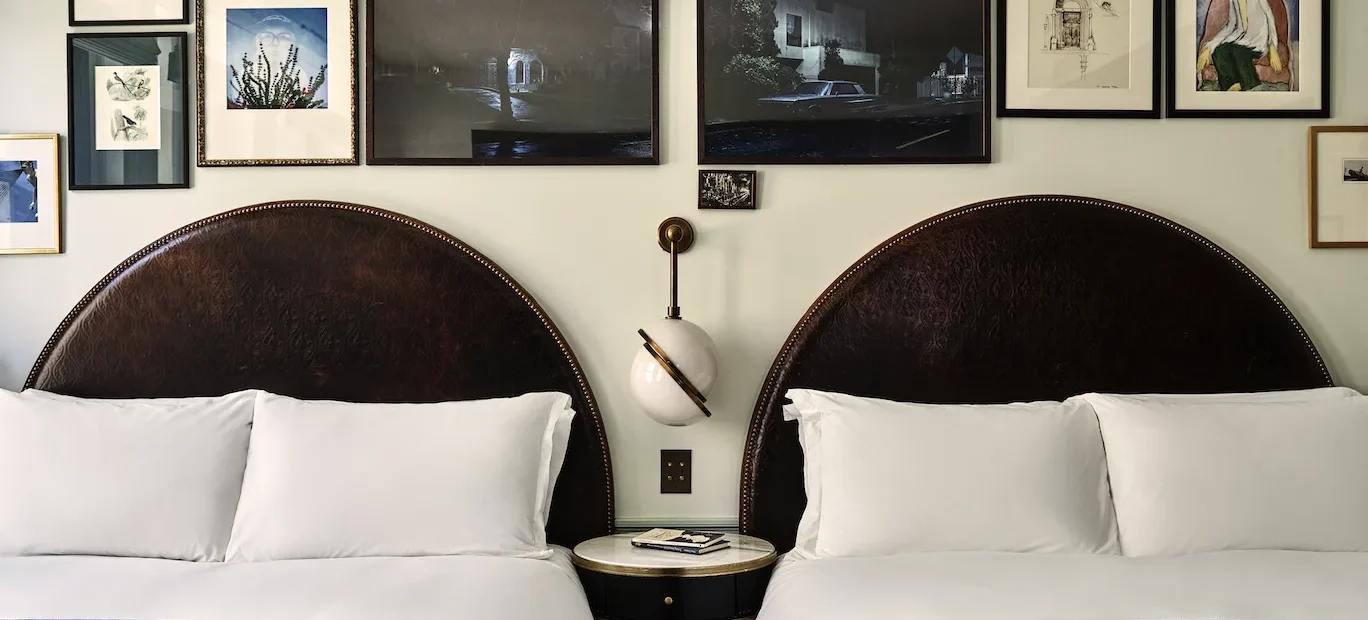 A hotel room with two large beds and a side table between them