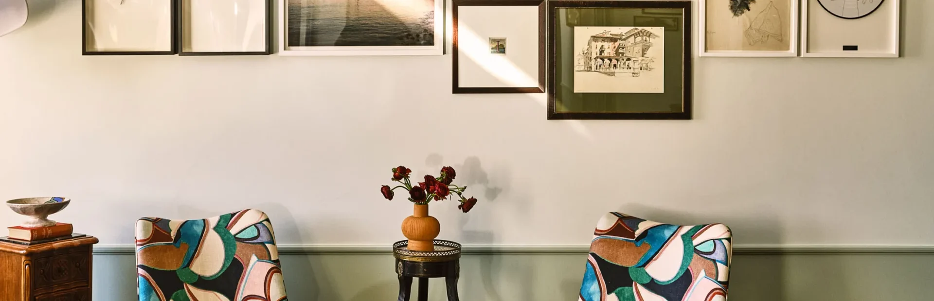 Two colorful patterned armchairs face a gallery wall inside a boutique hotel in Los Angeles.