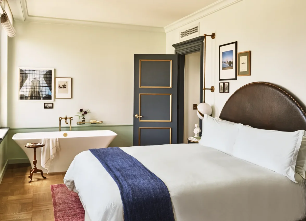 A hotel room with large bed and a soaking tub in the corner