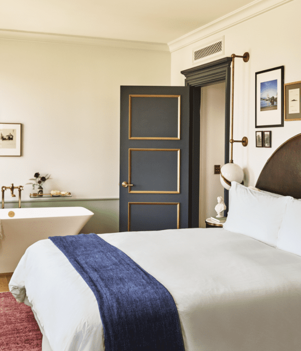 A hotel room with large bed and a soaking tub in the corner