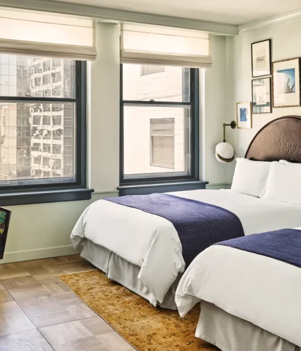 Two comfortable beds and a window-side seating area in a bright guest room at Hotel Per La in Los Angeles.