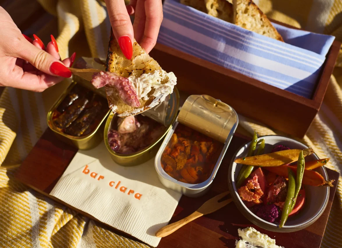 A guest enjoys artisan seafood and fresh vegetables on the sunny terrace of Bar Clara rooftop bar.