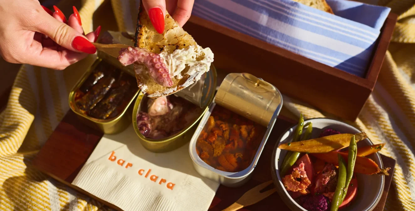 A guest enjoys artisan seafood and fresh vegetables on the sunny terrace of Bar Clara rooftop bar.