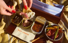 A guest enjoys artisan seafood and fresh vegetables on the sunny terrace of Bar Clara rooftop bar.