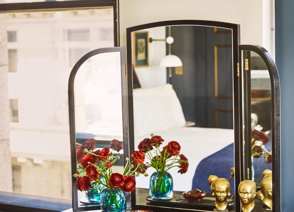 A black and gold trifold vanity table with red flowers and gold busts in a boutique Los Angeles hotel room.