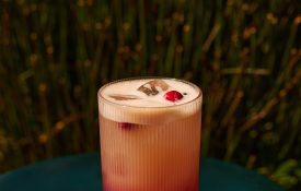 A layered pink and peach cocktail with a cranberry garnish at Bar Clara, a premier rooftop bar in Los Angeles.