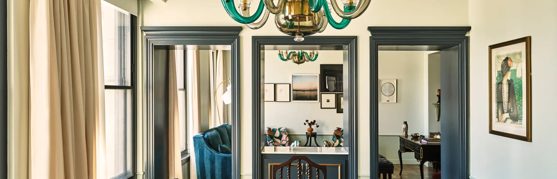 A polished dining table sits beneath a green glass chandelier in a boutique Los Angeles hotel suite.