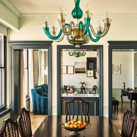 A polished dining table sits beneath a green glass chandelier in a boutique Los Angeles hotel suite.