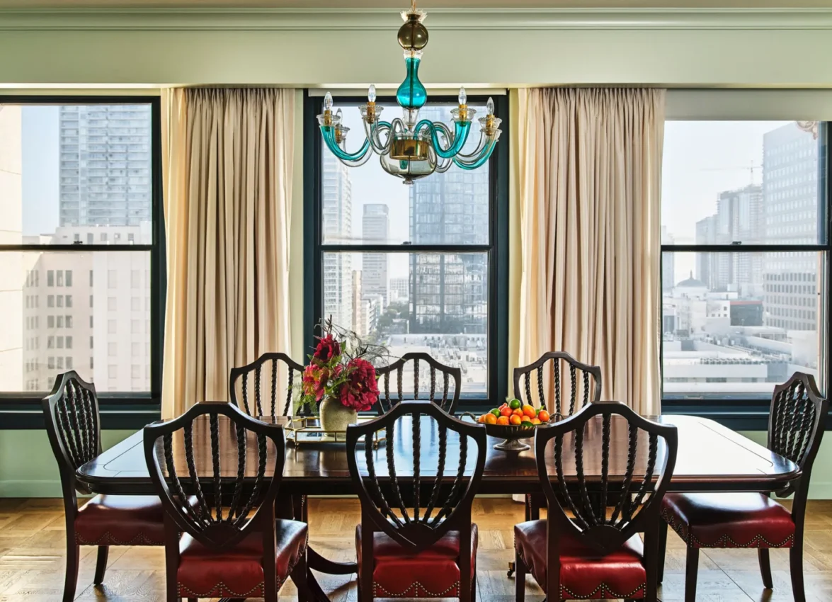 A luxury dining table with a turquoise chandelier and city views inside one of our hotel suites in Los Angeles.