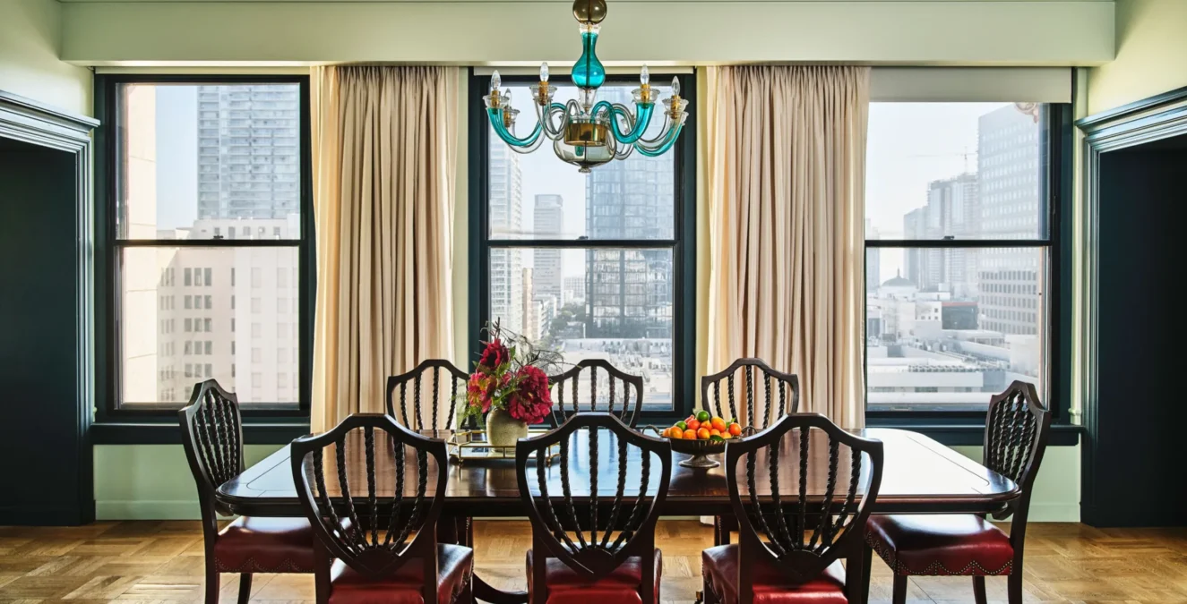A luxury dining table with a turquoise chandelier and city views inside one of our hotel suites in Los Angeles.