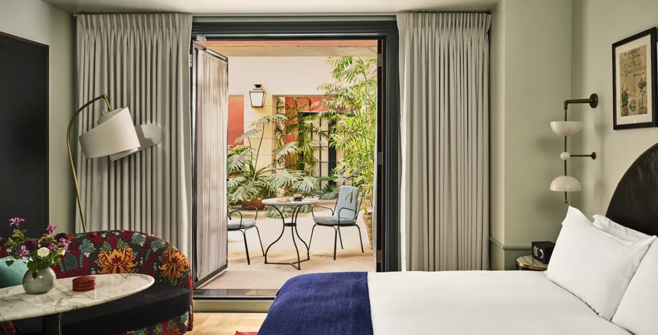 A refined Hotel Per La suite featuring stylish decor and a private patio with lush garden seating.