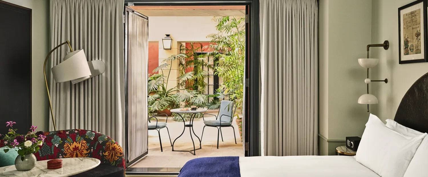 A refined Hotel Per La suite featuring stylish decor and a private patio with lush garden seating.
