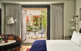 A refined Hotel Per La suite featuring stylish decor and a private patio with lush garden seating.