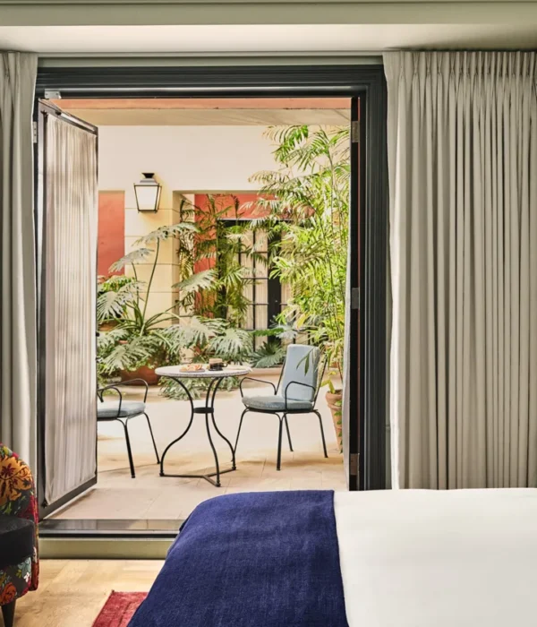 A refined Hotel Per La suite featuring stylish decor and a private patio with lush garden seating.