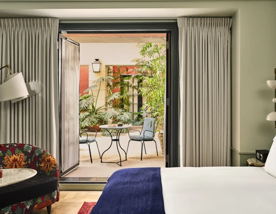 A refined Hotel Per La suite featuring stylish decor and a private patio with lush garden seating.