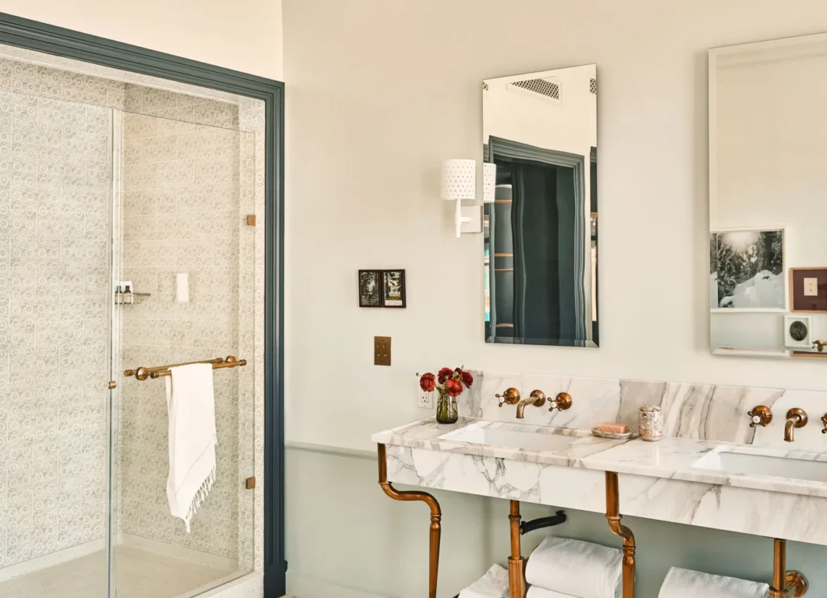 Double marble vanity and tiled walk-in shower in a luxury hotel suite in Los Angeles.