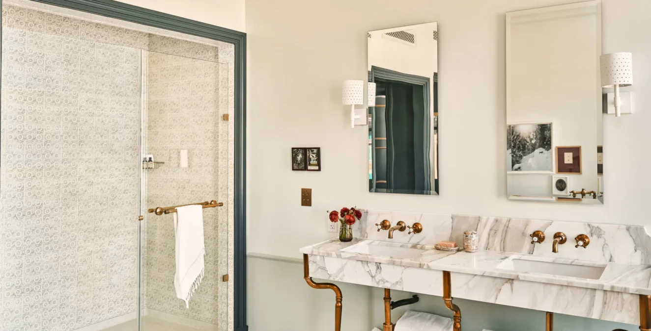 Double marble vanity and tiled walk-in shower in a luxury hotel suite in Los Angeles.