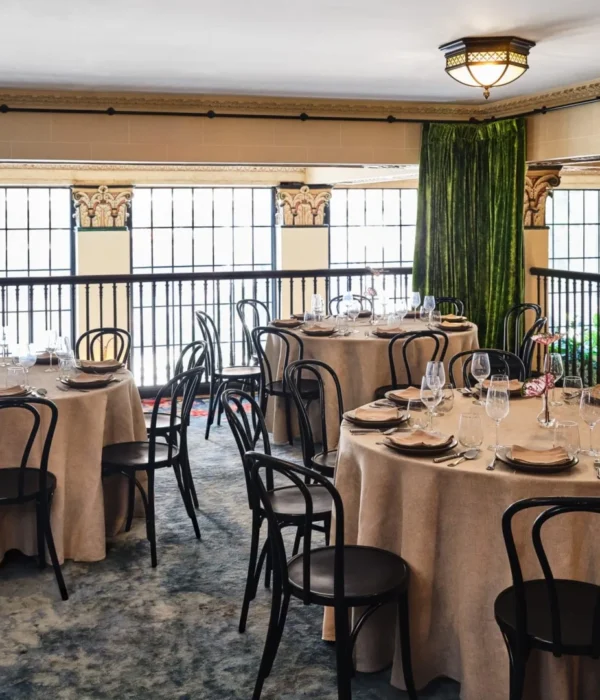 Formal round tables set for a banquet in an elegant Los Angeles event space with ornate columns and velvet curtains.