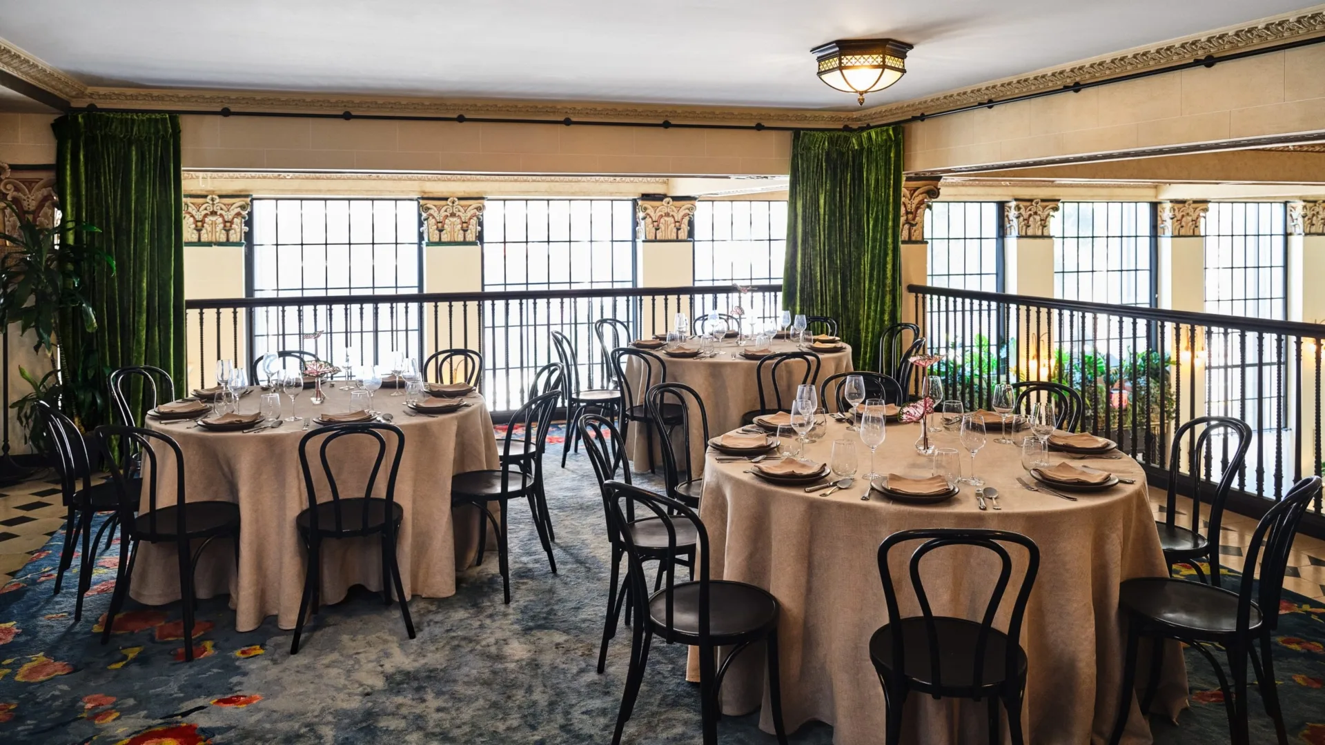 Formal round tables set for a banquet in an elegant Los Angeles event space with ornate columns and velvet curtains.