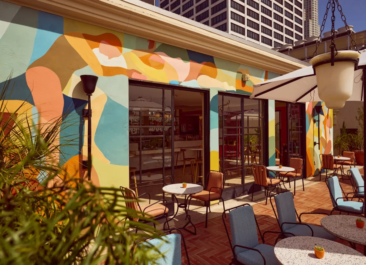 Colorful murals and outdoor tables offer a stylish setting at Bar Clara, a premier rooftop bar in Los Angeles, CA.