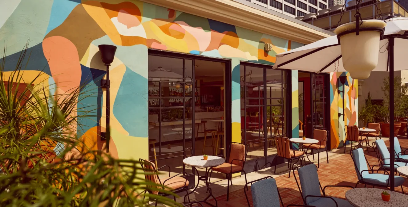 Colorful murals and outdoor tables offer a stylish setting at Bar Clara, a premier rooftop bar in Los Angeles, CA.