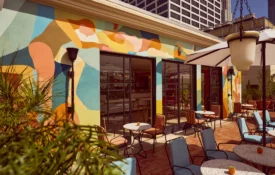 Colorful murals and outdoor tables offer a stylish setting at Bar Clara, a premier rooftop bar in Los Angeles, CA.