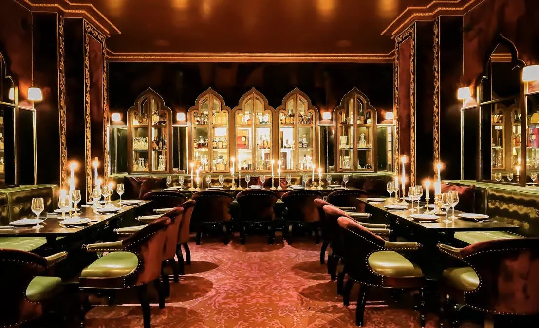 Tables set with candles and wine glasses in the ornate, dimly lit dining room of Ristorante Per L'Ora.