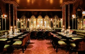 Tables set with candles and wine glasses in the ornate, dimly lit dining room of Ristorante Per L'Ora.