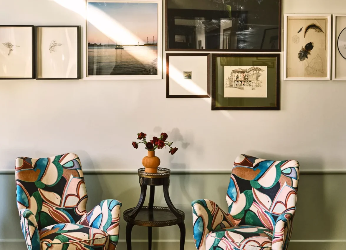 Two colorful patterned armchairs sit below an art gallery wall in a luxury boutique hotel in downtown Los Angeles.