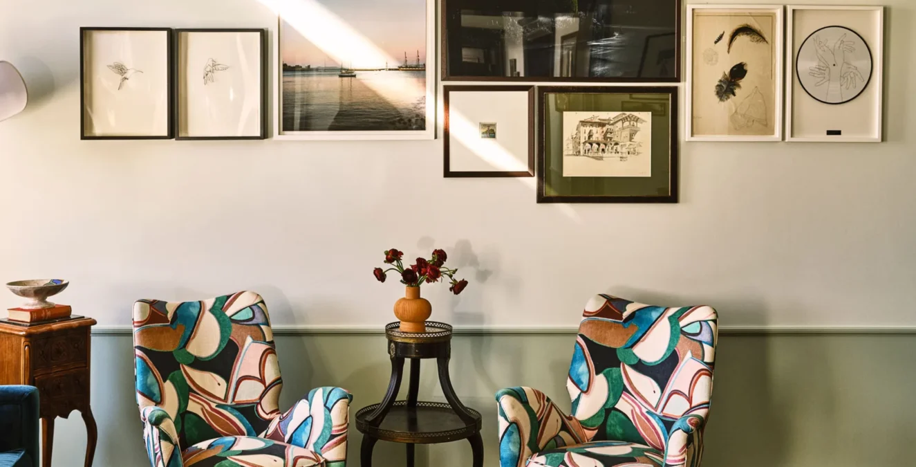 Two colorful patterned armchairs sit below an art gallery wall in a luxury boutique hotel in downtown Los Angeles.