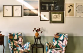Two colorful patterned armchairs sit below an art gallery wall in a luxury boutique hotel in downtown Los Angeles.