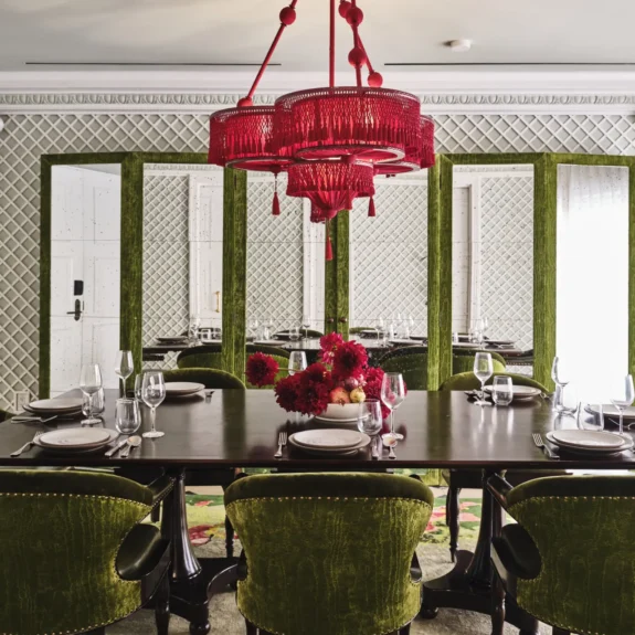 Green velvet chairs surround a long dining table at Ristorante Per L'Ora, an elegant event venue in Los Angeles.
