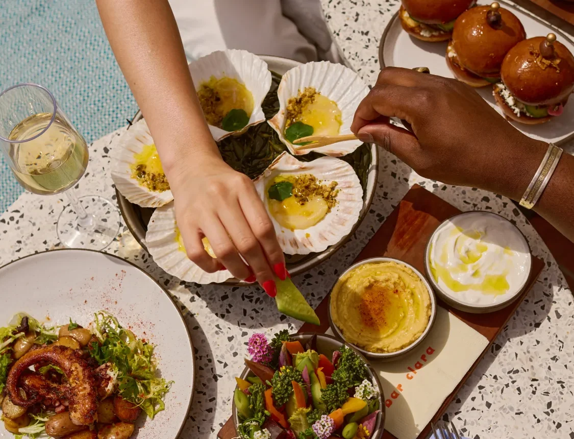 Diners enjoy fresh scallops and wine at Bar Clara, a premier rooftop bar and restaurant in downtown Los Angeles.