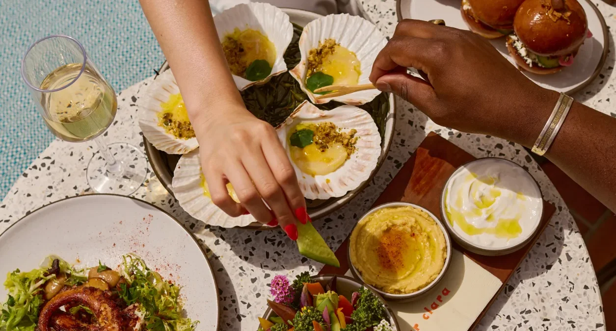 Diners enjoy fresh scallops and wine at Bar Clara, a premier rooftop bar and restaurant in downtown Los Angeles.