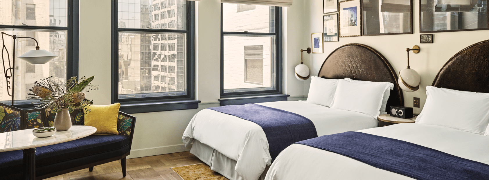 A hotel room with two large beds and a couch with a marble side table.