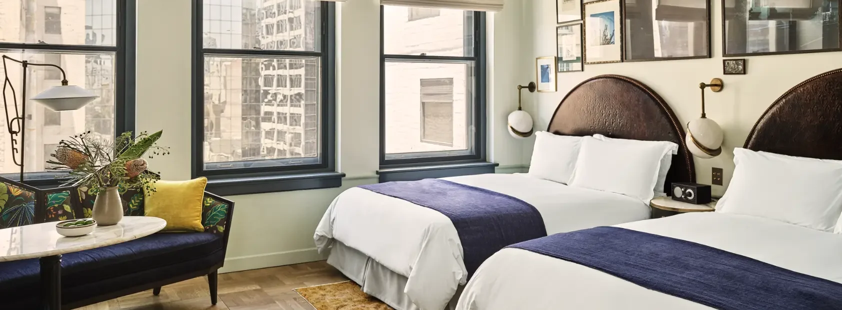 A hotel room with two large beds and a couch with a marble side table.