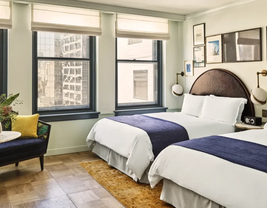 A hotel room with two large beds and a couch with a marble side table.