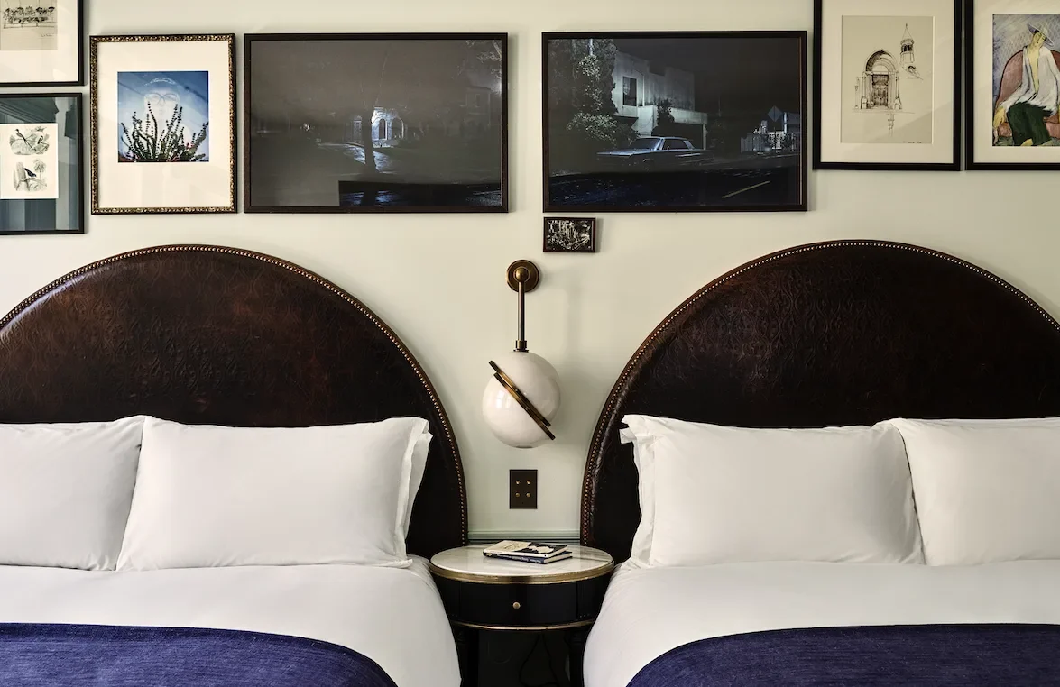 A hotel room with two large beds and a side table between them