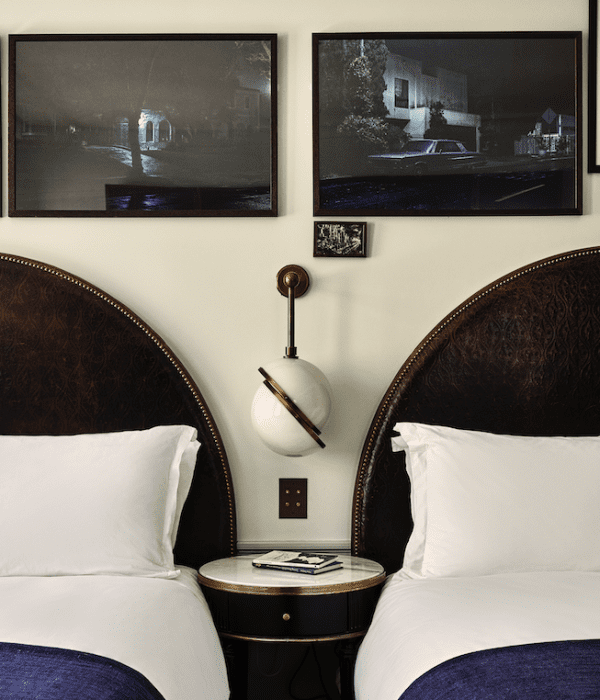 A hotel room with two large beds and a side table between them