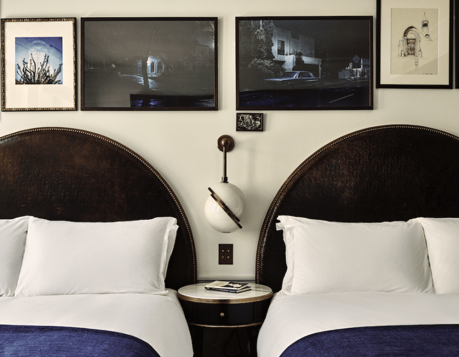 A hotel room with two large beds and a side table between them