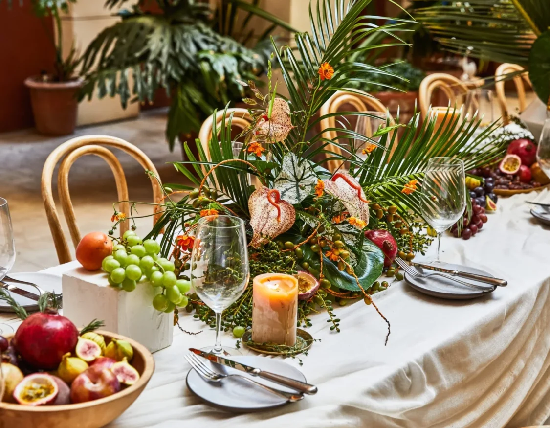An elegant table at Hotel Per La features tropical floral arrangements and fresh fruit for a wedding celebration.