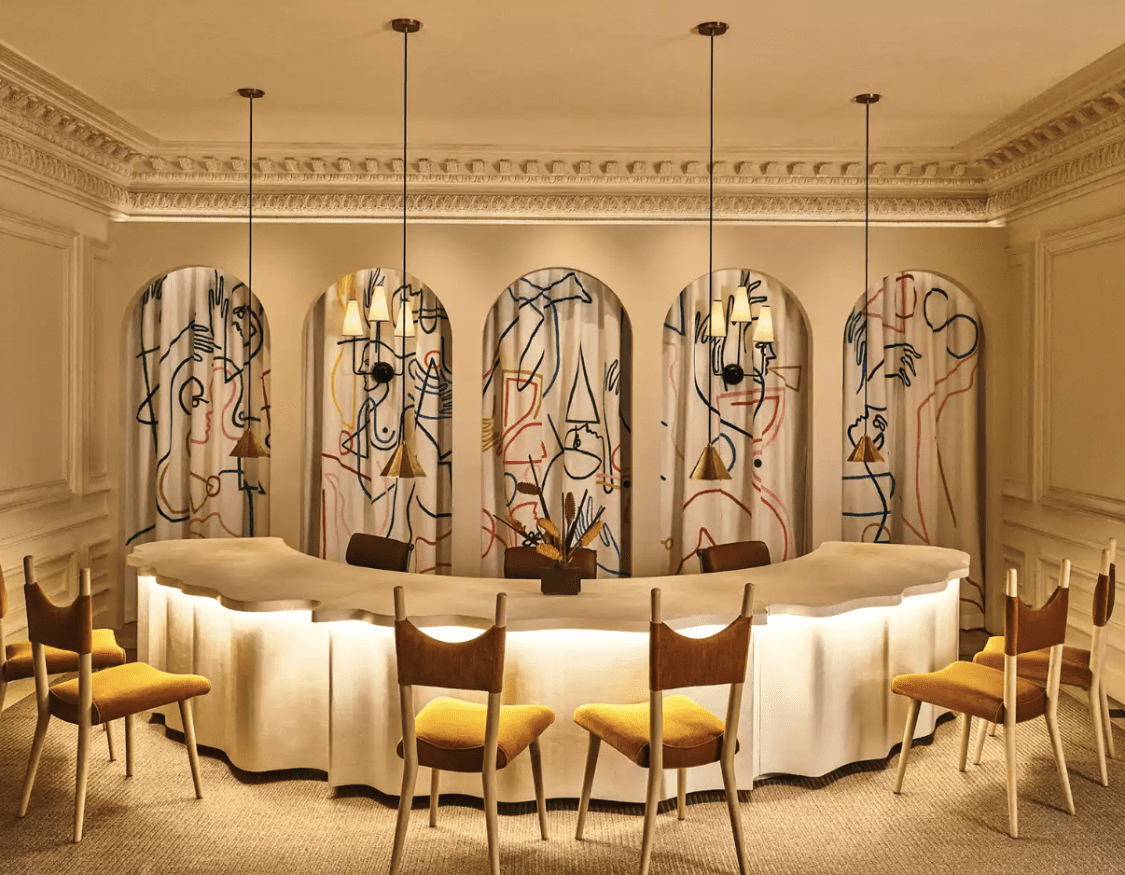 An elegant room with an arched table and gold chairs