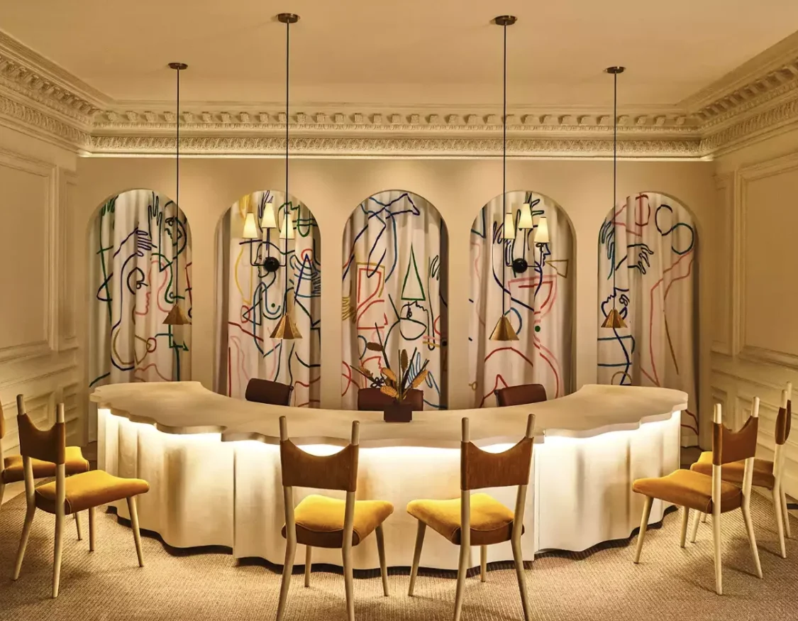 An elegant room with an arched table and gold chairs