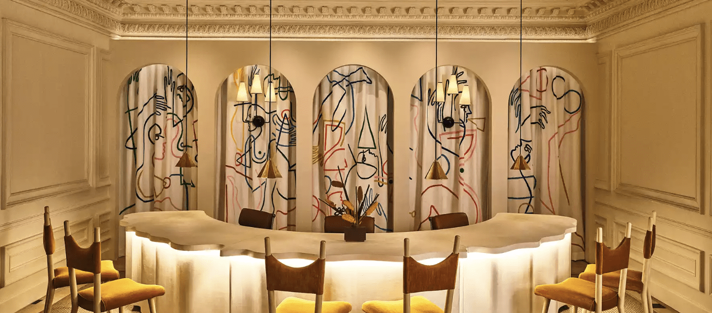 An elegant room with an arched table and gold chairs