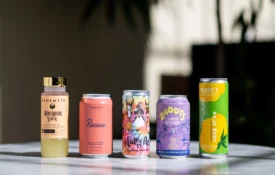 A colorful lineup of craft canned cocktails and bottled drinks on a marble counter at Bar Clara in Los Angeles.