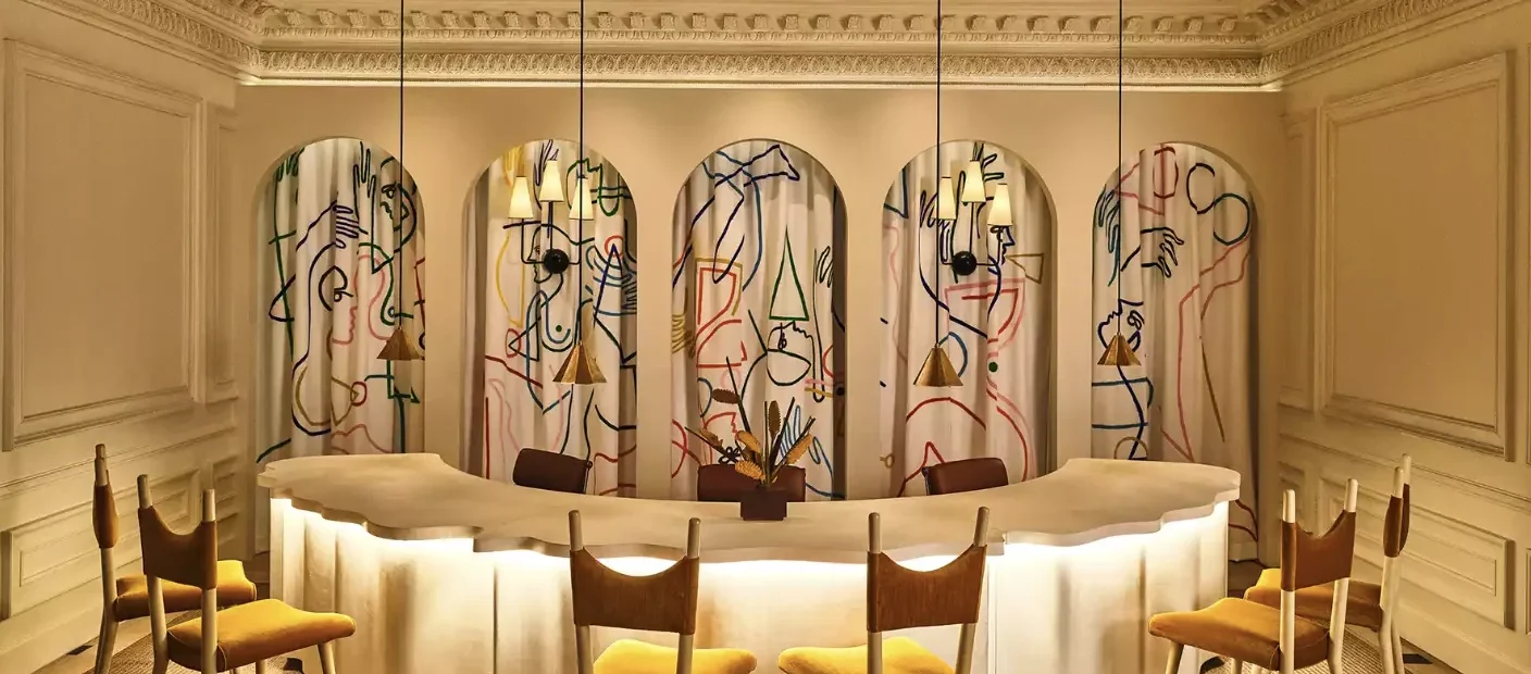 Yellow chairs at a glowing counter in a sophisticated Los Angeles event space featuring abstract art-covered arches.