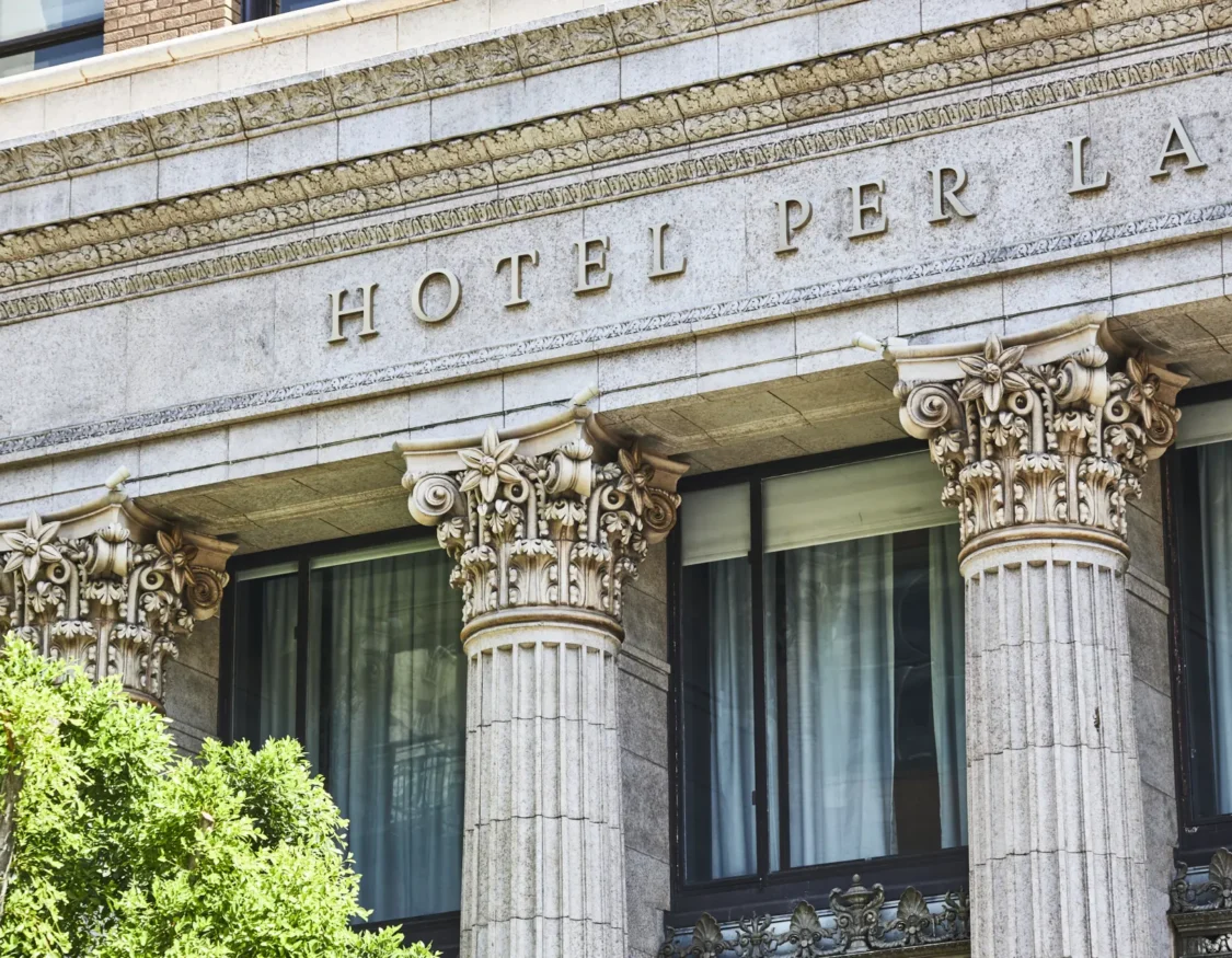 Detailed view of the ornate stone facade and classical columns at Hotel Per La, a luxury boutique hotel in Los Angeles.