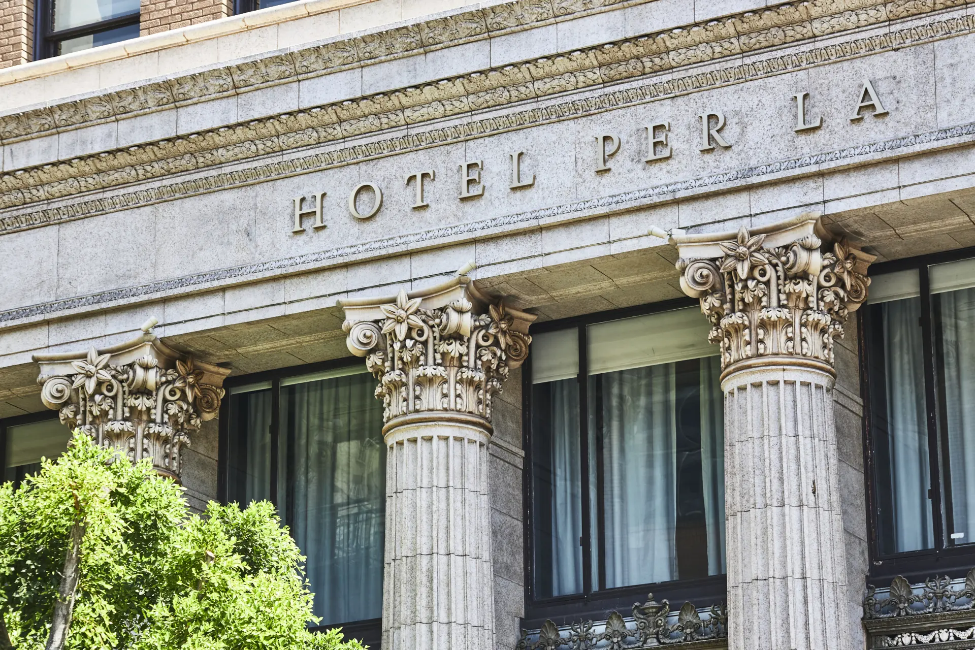 Detailed view of the ornate stone facade and classical columns at Hotel Per La, a luxury boutique hotel in Los Angeles.